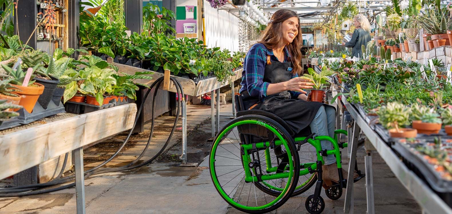A woman in a folding wheelchair browsing plants in a garden centre